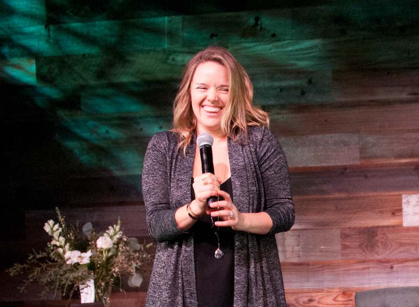 Meghan laughing with a microphone on stage