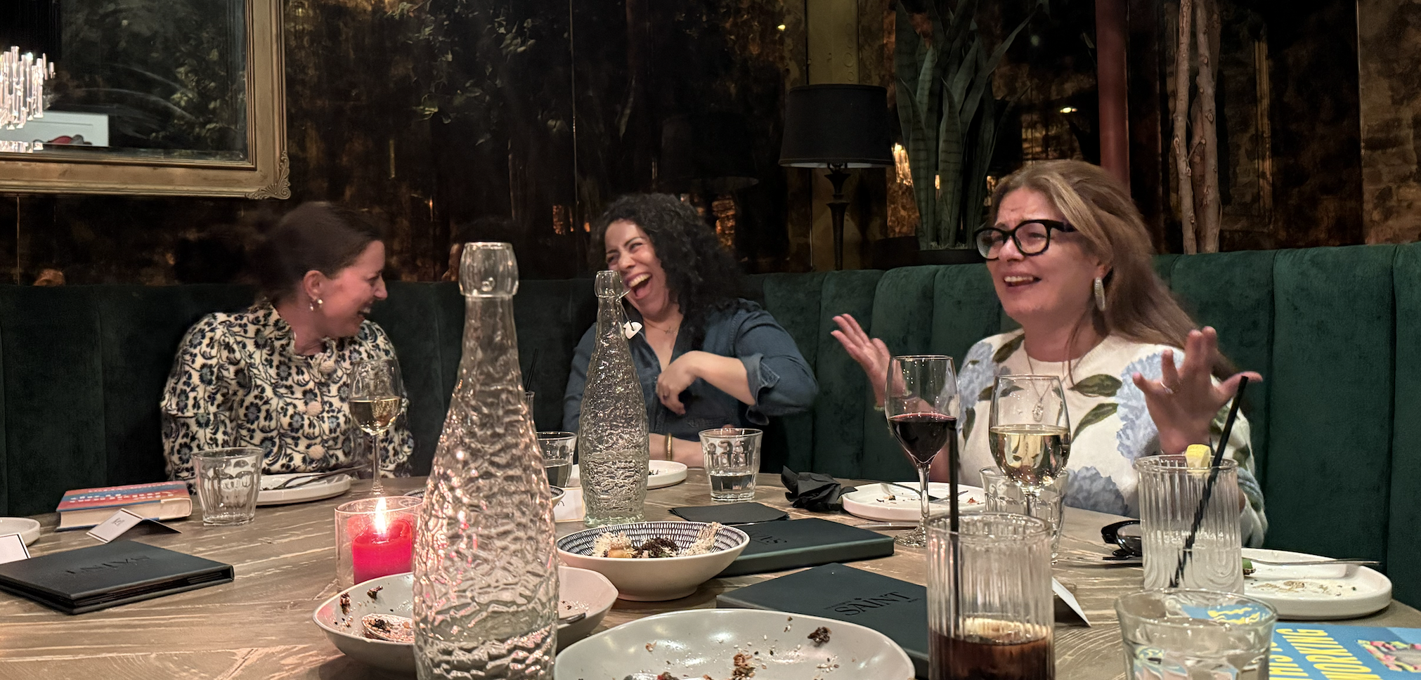 Women laughing together over dinner at a past gathering